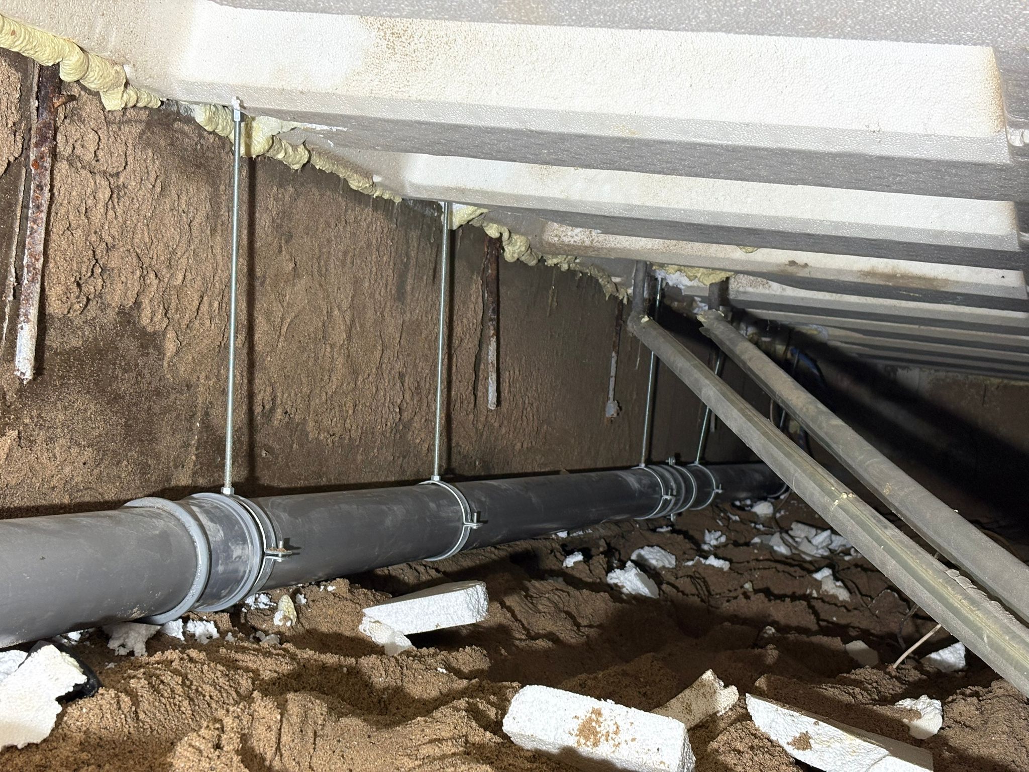 PVC-hoofdleiding bevestigd aan funderingsmuur in kruipruimte Dordrecht