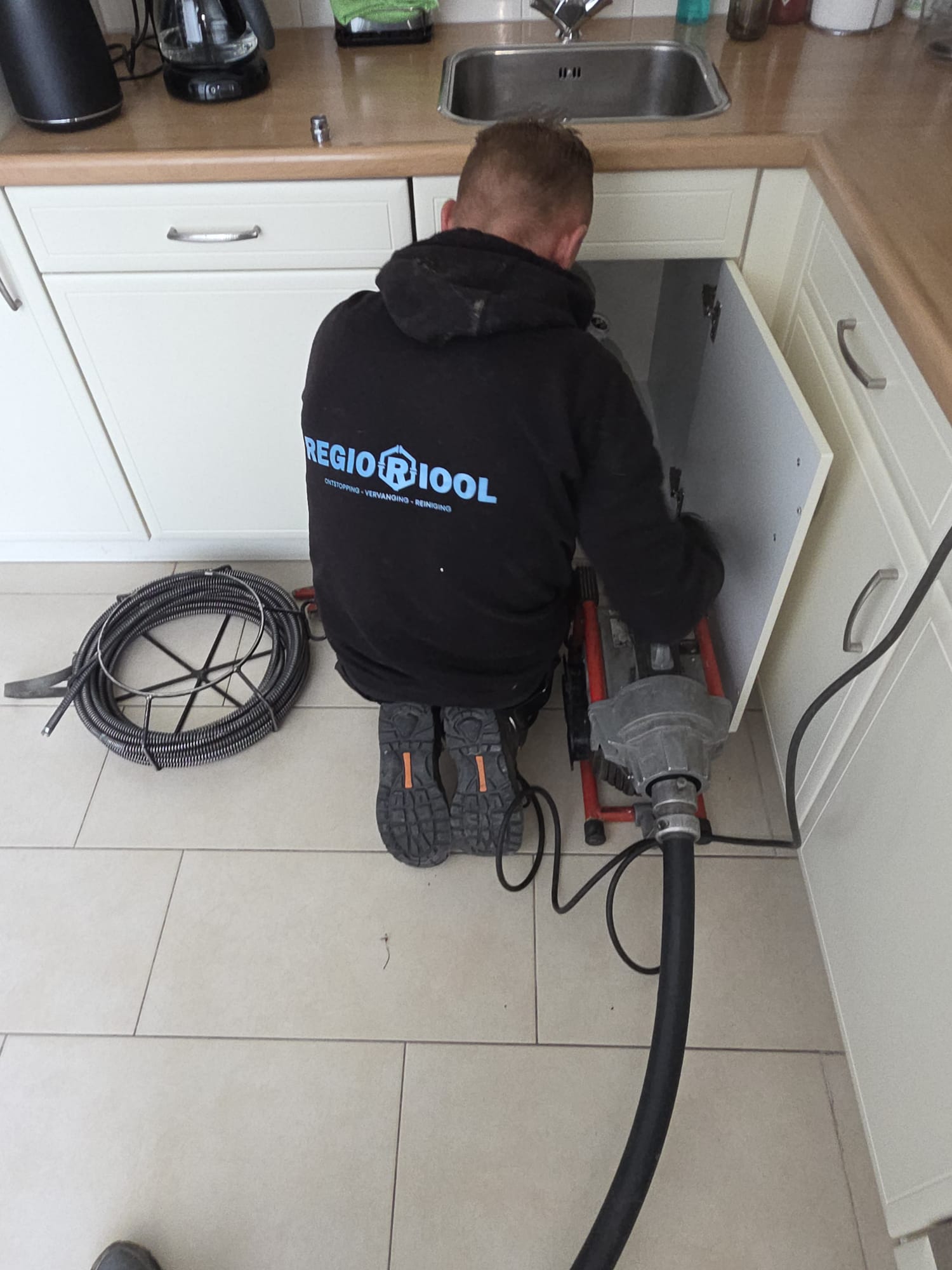 Regioriool-monteur ontstopt keukenafvoer met elektrische veermachine in Delft