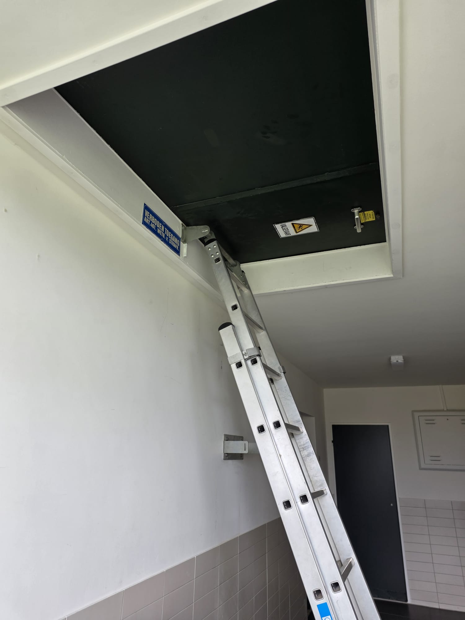 Ladder naar dakluik in trappenhuis flat Rotterdam voor standleiding-toegang