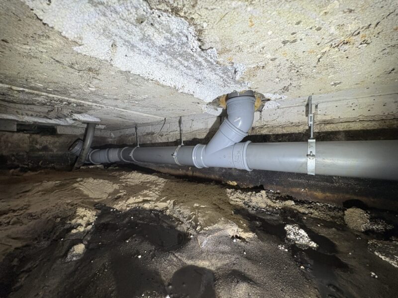 Nieuw aangebrachte PVC-binnenriolering met T-stuk en beugels in de kruipruimte van een woning in Berkel en Rodenrijs