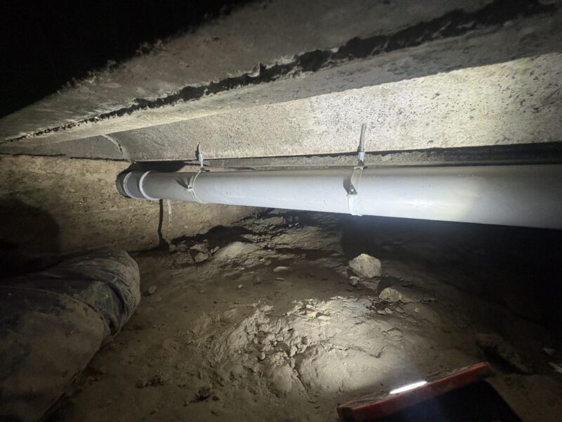 Gemonteerde nieuwe rioolleiding met beugels in de kruipruimte van een woning in Zoetermeer