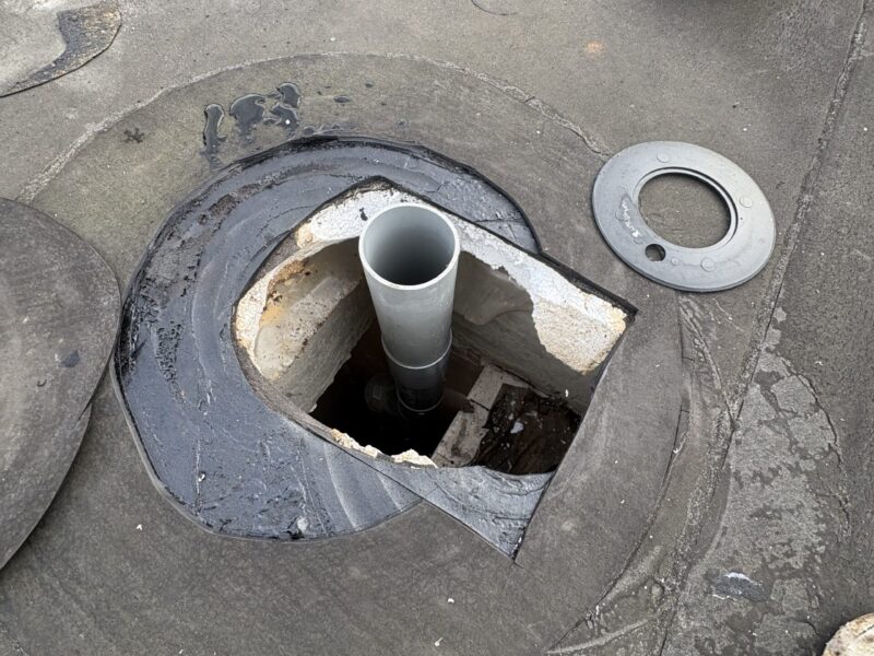 Close-up van open dakdoorvoer met verlengde PVC beluchtingsleiding en losliggende dakdoorvoer onderdelen op plat dak in Alphen aan den Rijn