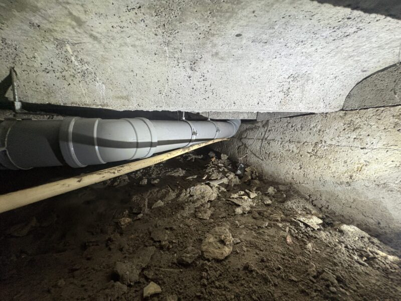 Nieuw PVC-riool met bevestigingsbeugels langs funderingsbalk in kruipruimte Zoetermeer