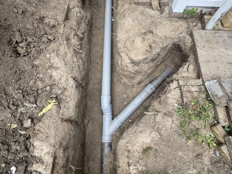 Vrijgelegde PVC-rioolleiding in gegraven sleuf buiten de woning in Rijswijk